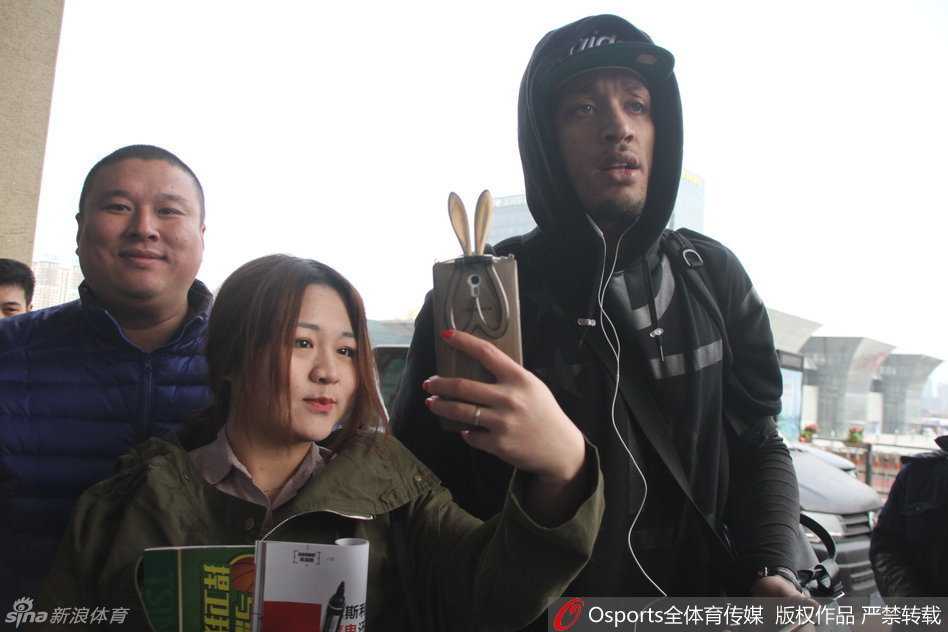 在候车大厅的休息区，比斯利坐在椅子上低头查看手机，身边是刚刚签过名的纪念品，而他的身后，仍有球迷依依不舍地守护着，不愿离去。