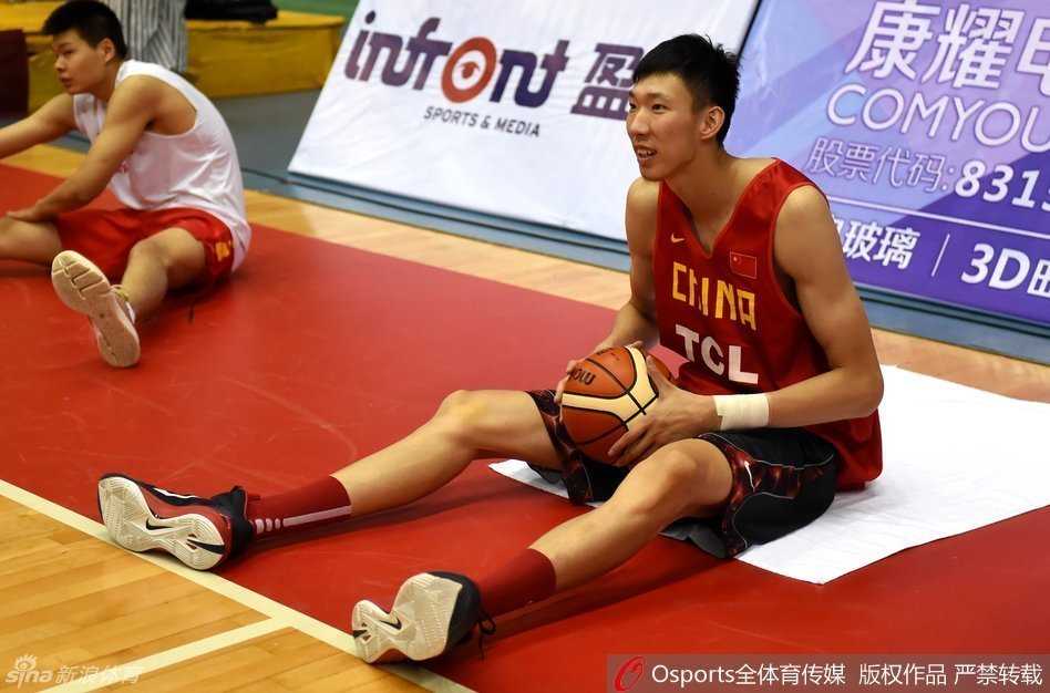 周鹏咧着嘴笑得开怀，正在打趣身旁的队友，那股坏笑的样子充满了队内的欢乐气氛；易建联则坐在场边的长椅上，双手放在腿上，表情沉静地观望着场上的训练。