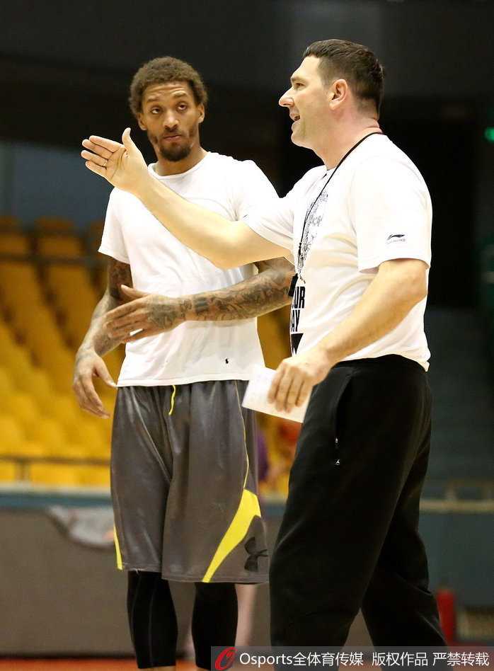 训练间隙，比斯利用毛巾擦着汗，微笑着与身边的队友杰特交谈，两人似乎在交流着刚才某个回合的配合心得，气氛融洽。