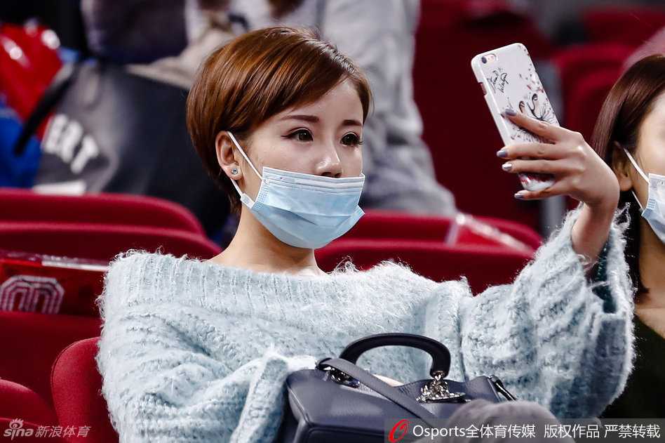 她拿起手机对着赛场记录下这精彩的瞬间，嘴角不自觉地上扬，眼中满是温柔与笑意，仿佛透过镜头看到了最想看的风景。