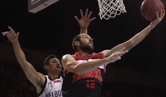 场边教练神情严肃地给队员布置战术，球员们围成一圈认真聆听，身后是热情的主场球迷