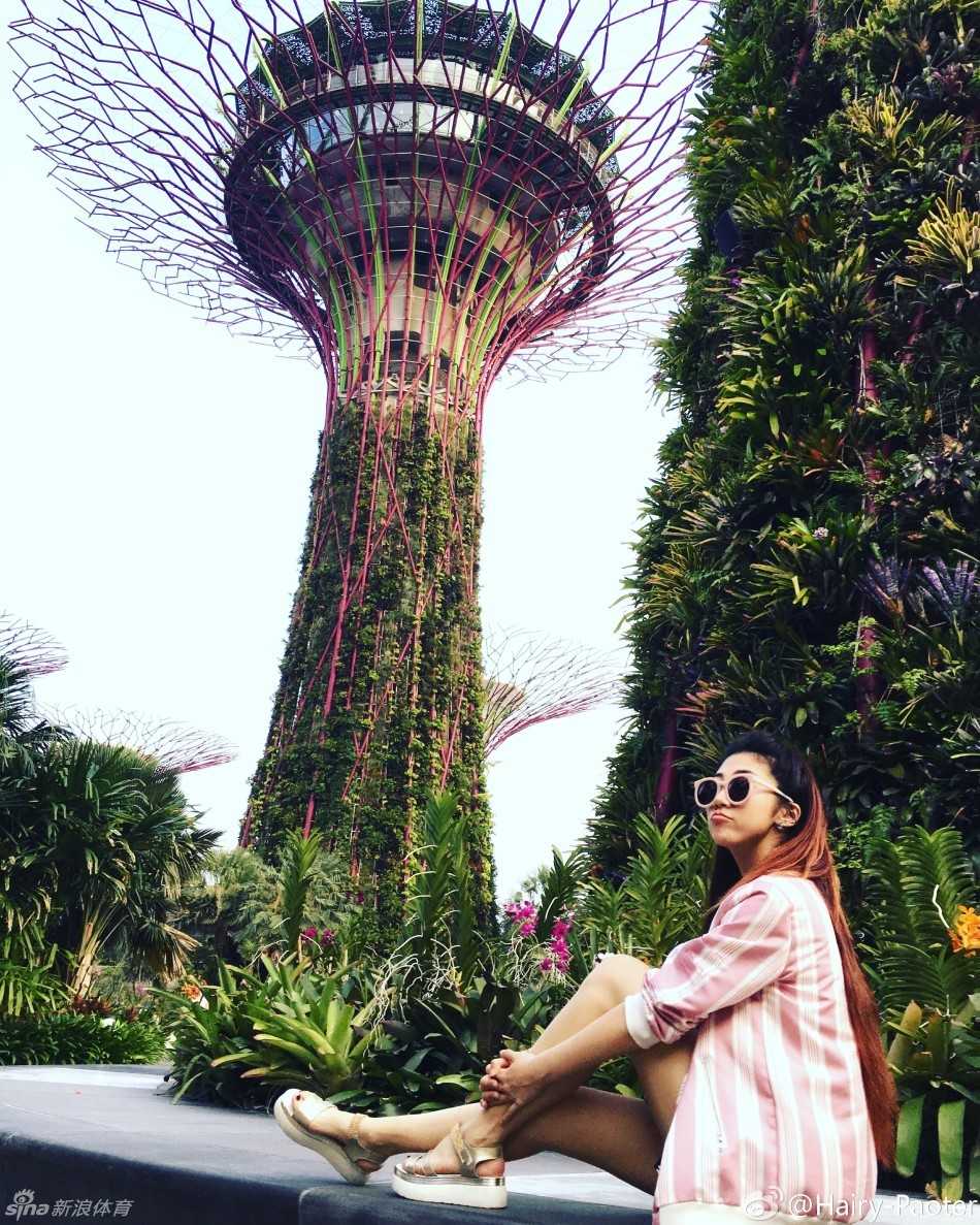 性格调皮的李跑登上一处台阶，回眸对着镜头嘟嘴卖萌抱美腿，俏皮可爱的模样宛如少女