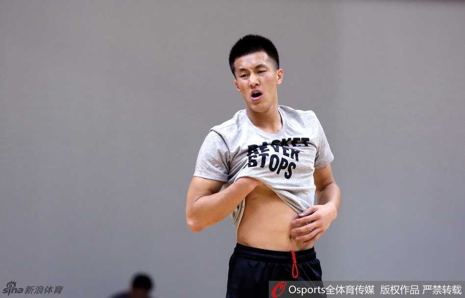 锋线悍将李根正在进行赛前的拉伸训练，他神情专注地压腿，每一块肌肉的延展都透露出职业球员对身体管理的极致追求。