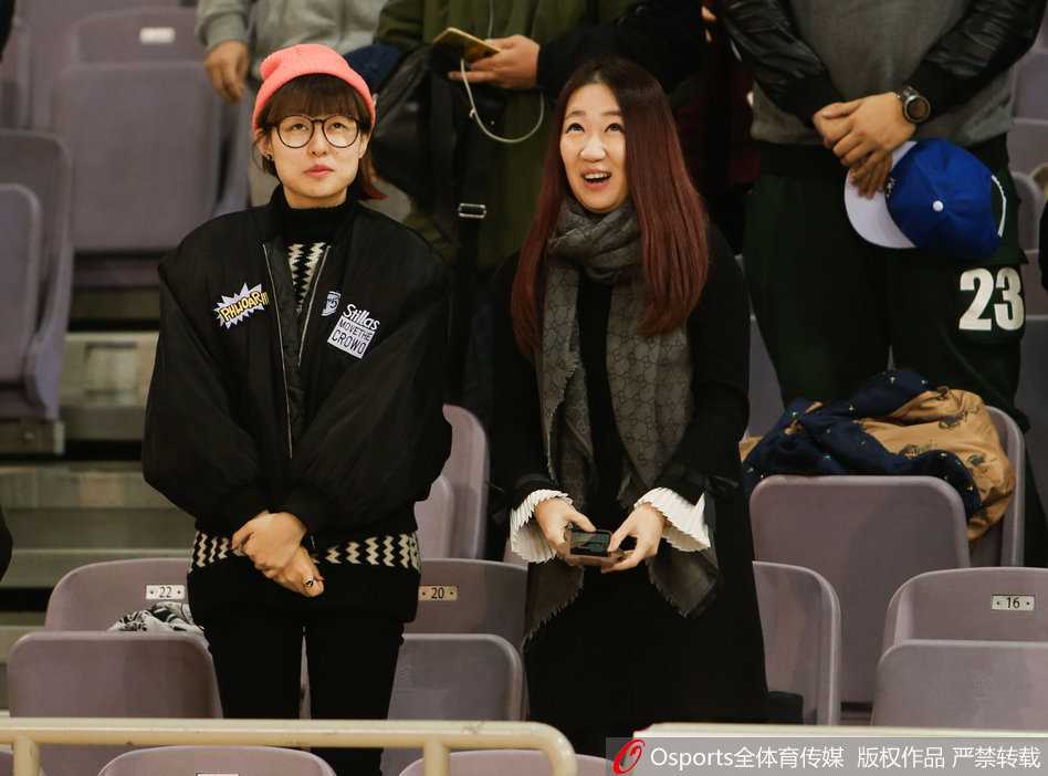 女球迷捂嘴浅笑，羞涩神情被大屏幕捕捉，眼睛弯成两道月牙