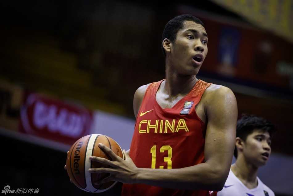 面对菲律宾球员的围堵，丘天犹如内线铁塔，高高跃起准备单手抛投，肌肉线条在球衣下若隐若现，充满力量感。