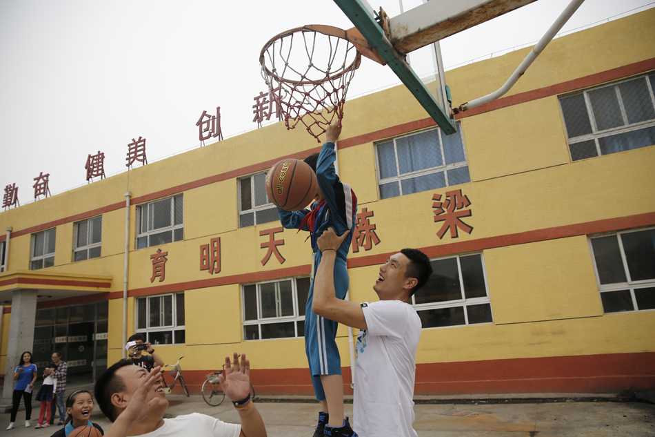 翟晓川与全校师生的大合影中，孩子们举着崭新的文体用品欢呼雀跃，背景是略显斑驳的教学楼，但每个人的笑容都如同阳光般灿烂