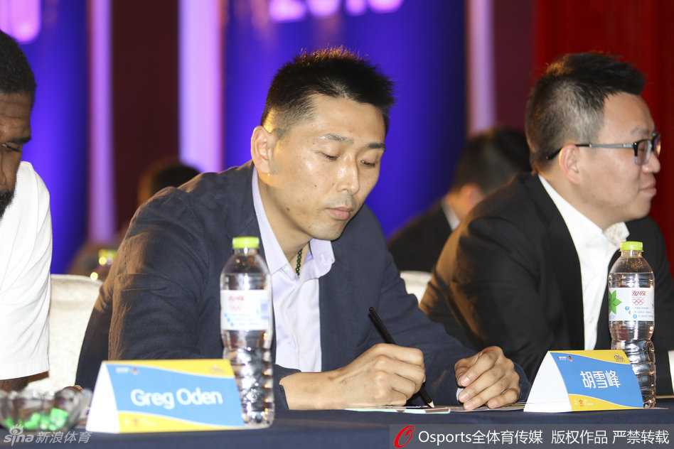 奥登和胡雪峰并肩站在背景板前合影，两人神情轻松自然，身后的邮轮图案暗示着即将启航的跨界合作，这一刻定格了两人合作的美好瞬间。