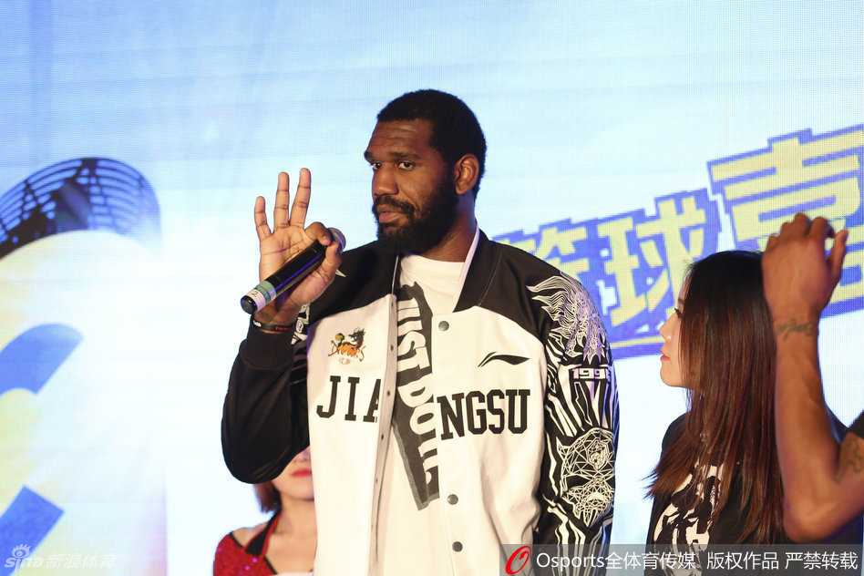 奥登俯身低头与一位娇小的美女球迷亲切交流，巨大的身高差形成有趣对比，他表情认真而温柔，完全不像球场上的凶悍内线。