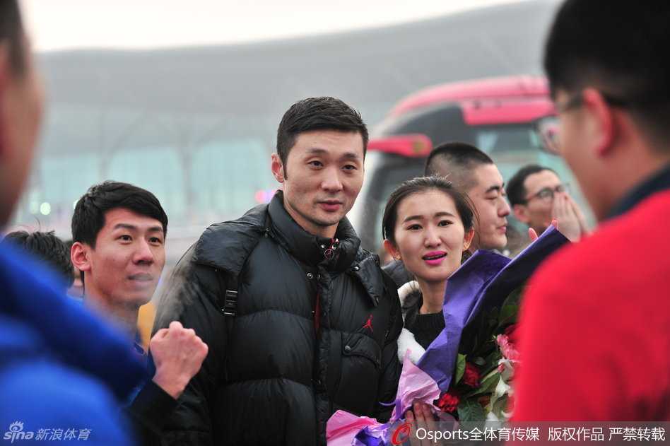 老将刘炜面带微笑，俯身在一件新疆队球衣上认真签名，身边围着几位满眼期待的球迷。