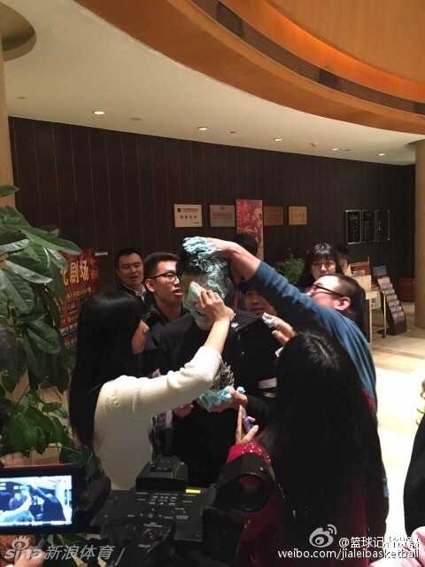 郭艾伦被热情的球迷围在中间，蓝色的蛋糕奶油几乎糊满了他的脸颊和头发，他试图躲闪却难掩眼中的笑意