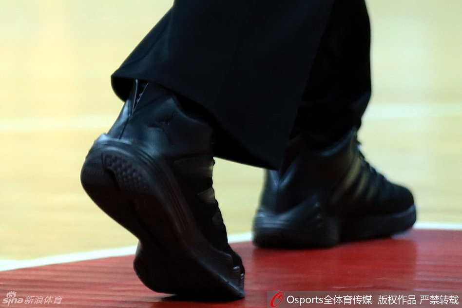 裁判与技术台人员交流，抬腿搁在记录台边缘，鞋底的飞人标志和磨损的鞋跟诉说着比赛的激烈与执法的奔波