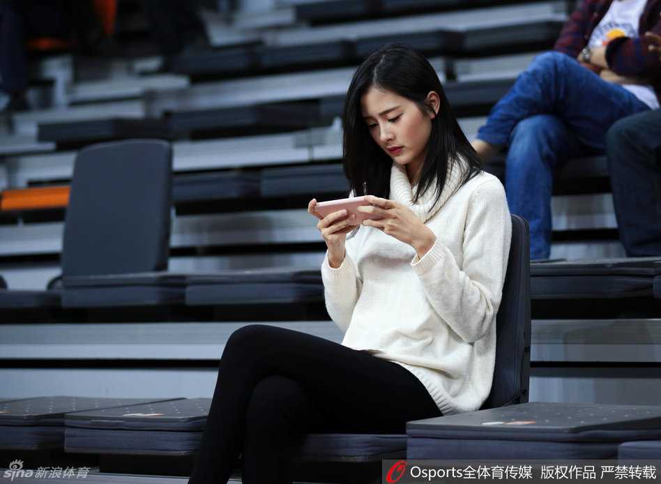 戴着眼镜的斯文女球迷在球队陷入僵局时神情专注，眼神中透露出对胜利的渴望，清秀的面容在助威声中格外醒目。