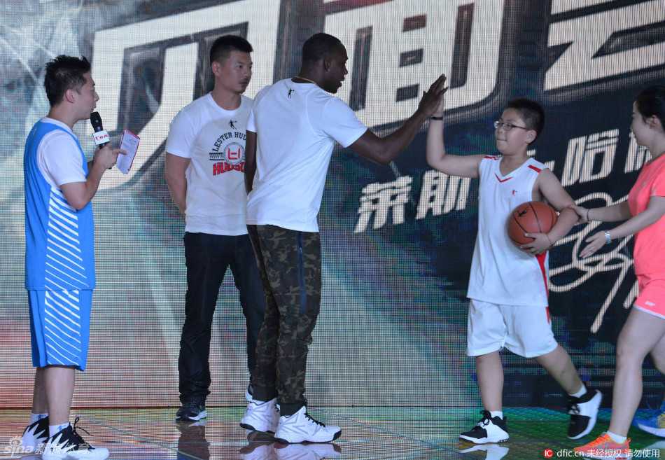 辽宁男篮哈德森沈阳收徒 与爱女共度温馨球迷日 哈德森怀抱着粉丝送上的鲜花,身旁站着可爱的女儿,父女俩一起对着镜头露出幸福的笑容,背景是热情的沈阳球迷。