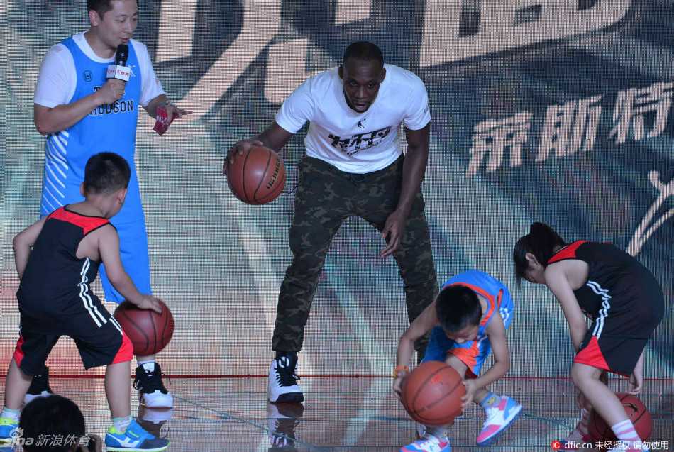 辽宁男篮哈德森沈阳收徒 与爱女共度温馨球迷日 哈德森抱着女儿站在台上,父女俩一起俯瞰台下密密麻麻的球迷,女儿的小手搭在爸爸肩上,画面充满了温情与归属感。