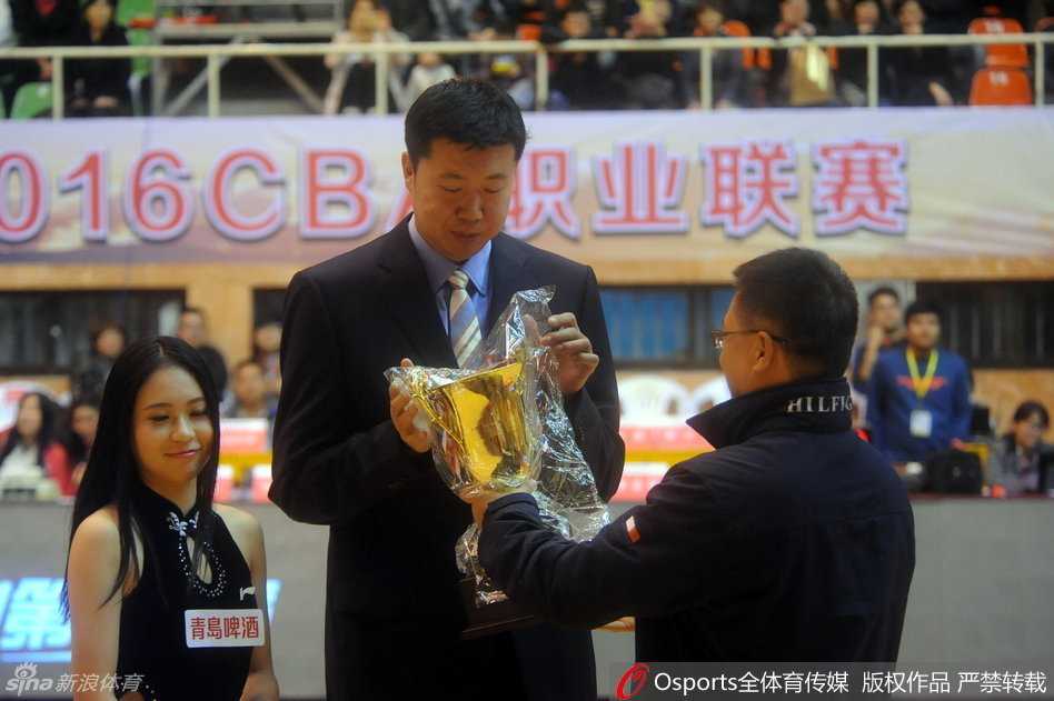 铁血柔情终成忆:王治郅的荣耀告别与八一精神传承 在比赛现场的背景板前,王治郅与一位优雅的女嘉宾共同捧着奖杯合影,记录下这历史性的瞬间,标志着一位传奇球员职业生涯的圆满落幕。