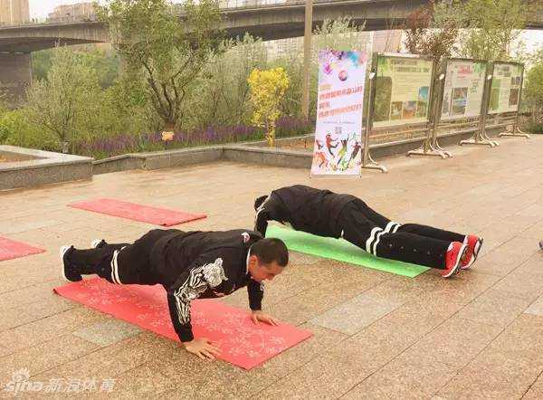 阿不都沙拉木在闯关点认真地做着俯卧撑，动作标准有力，路旁的志愿者正在为他计数盖章。