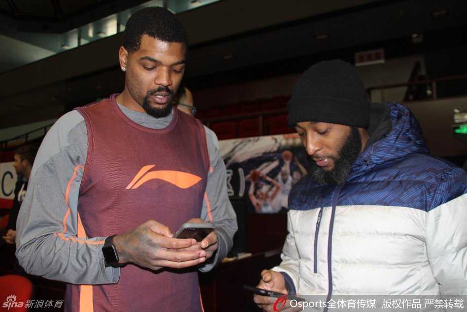 赛前热身时，山东队外援AJ·普莱斯与四川队外援约什·史密斯在场边交谈甚欢，普莱斯拿出手机，两人正在交换联系方式，脸上洋溢着友好的笑容。
