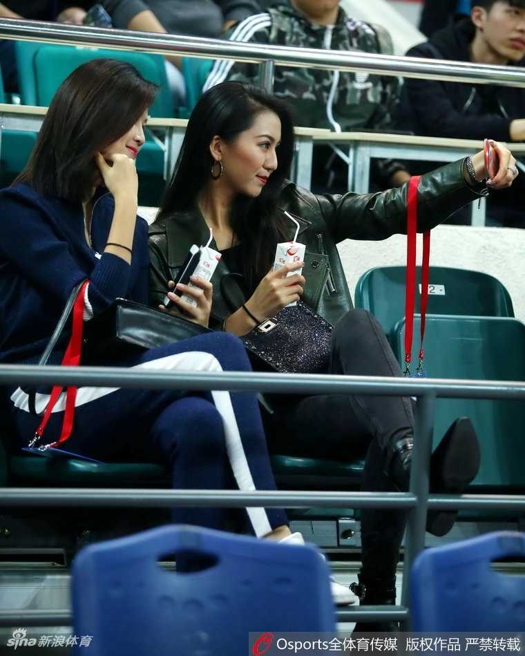 一位身穿白色上衣的美女球迷在人群中回眸，她的眼神清澈而坚定，仿佛在告诉所有人，女生同样可以是篮球场上最专业的观众，那份从容与自信美得让人移不开眼。