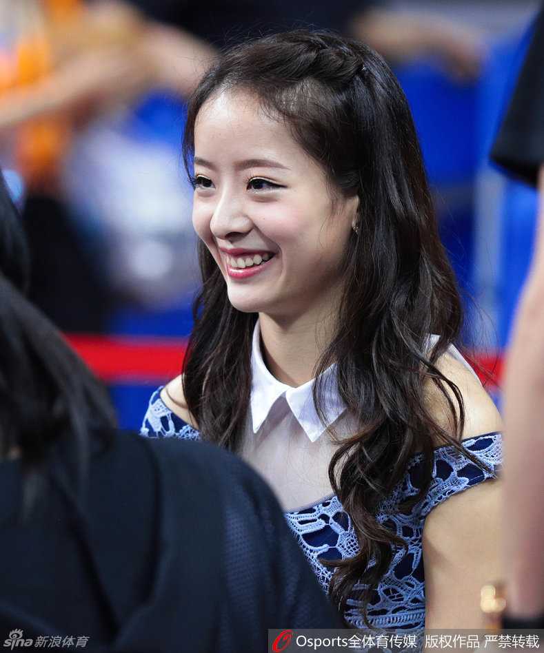 周鹏妻子刘美身穿鲜艳红衣在场边为广东队助威，神情专注，温婉大气中透露出对丈夫的坚定支持