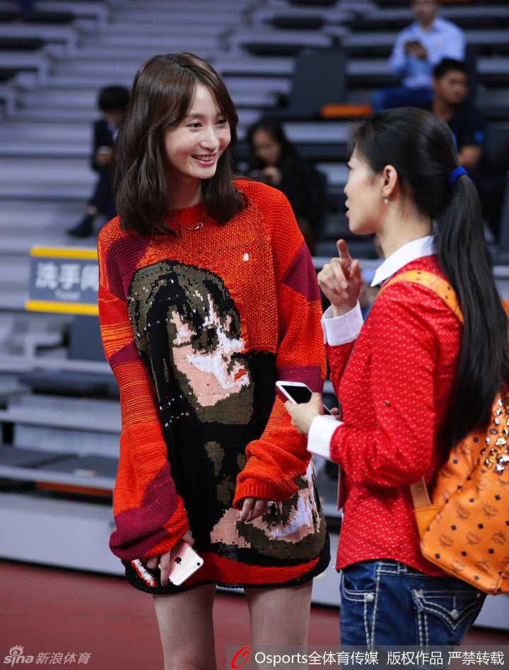 广东队周鹏妻子刘美与朋友在场边交谈，一袭红衣的她笑容温婉，成为赛场边的一道风景线
