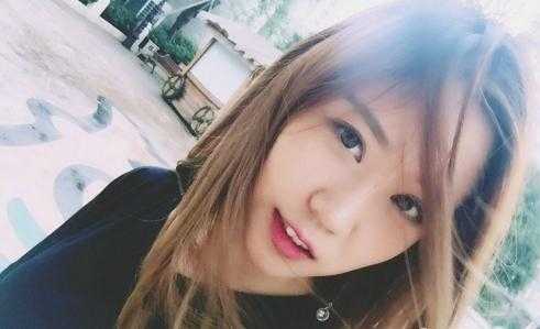 一位啦啦队员身穿一袭白色连衣裙，静静地坐在那里，清纯可人。她侧身而坐，身体的柔美曲线在裙摆的衬托下若隐若现，展现出一种含蓄而优雅的静态美。