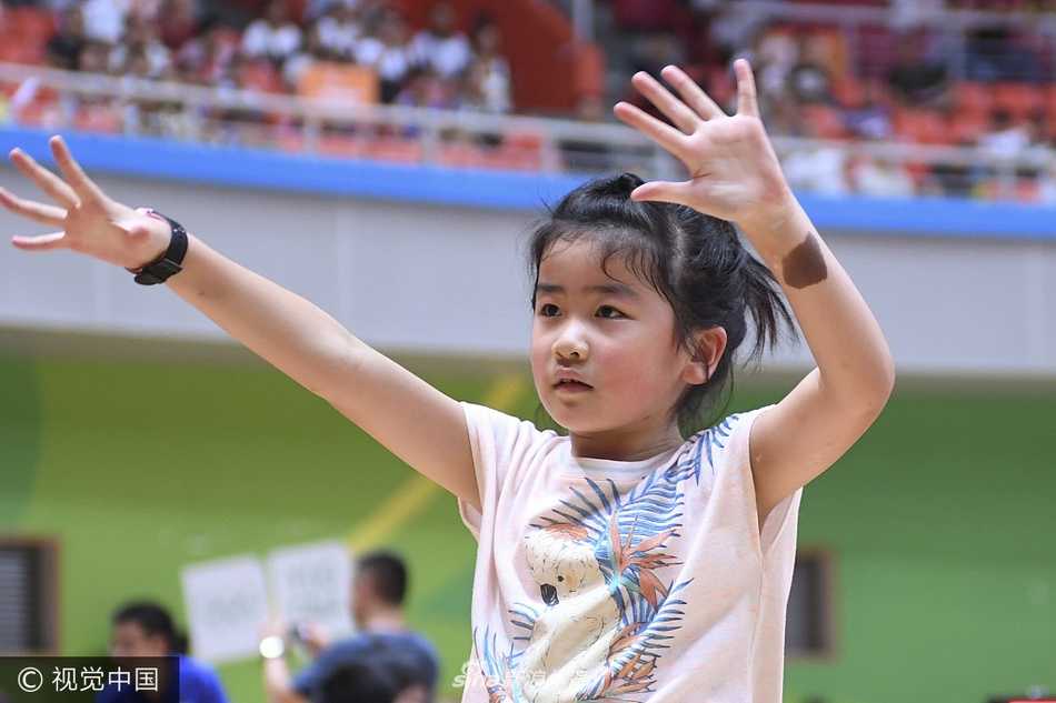 沁蕾学着大人的样子，将篮球高高举过头顶，小手用力一推，篮球划出一道小小的抛物线，眼神里充满了对篮筐的渴望。