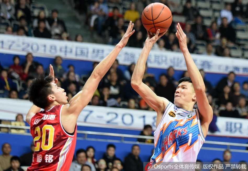 上海队外援明纳拉斯在八一队内线完成一记势大力沉的单手劈扣，他整个人悬挂在篮筐之上，对手的防守球员只能无奈地仰头观望。