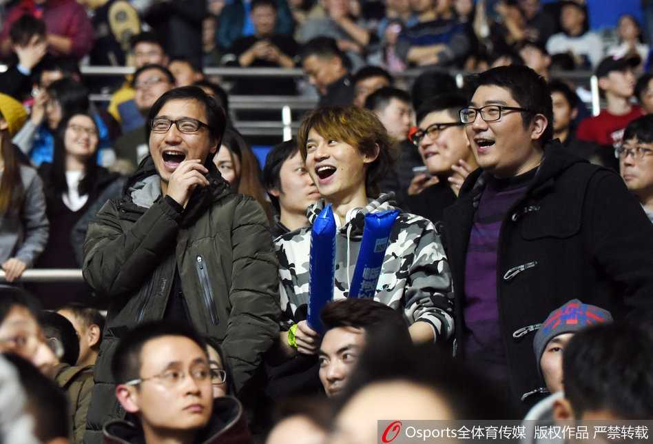 看台上，两位男性球迷激动地起身站立，他们手中展开的纸上用加粗的记号笔写着