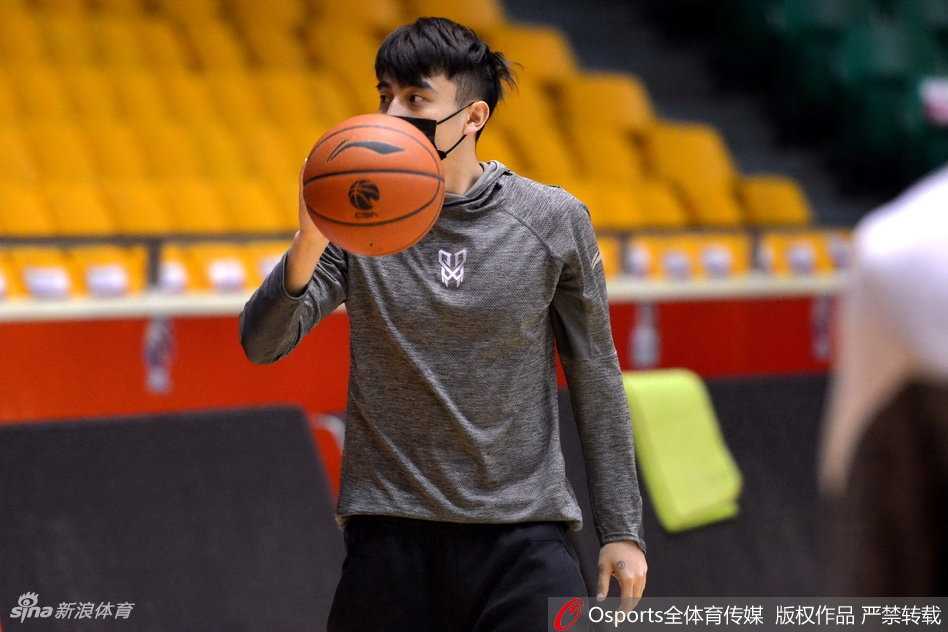 上海男篮将帅在赛前训练中围成一圈，教练刘鹏紧握战术板，目光坚毅地向球员们布置最后的防守策略，气氛紧张而专注。