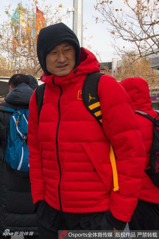 在机场到达大厅，主教练杜锋停下脚步，面带微笑地为热情的澳大利亚当地球迷在纪念品上签名，展现了男篮队员的亲和力。