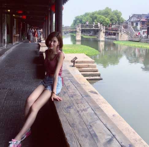 两位空姐并肩站在浅海中，相视而笑。她们穿着色彩明快的度假长裙，手牵手享受着海浪的轻抚，姐妹情深与夏日气息完美融合。