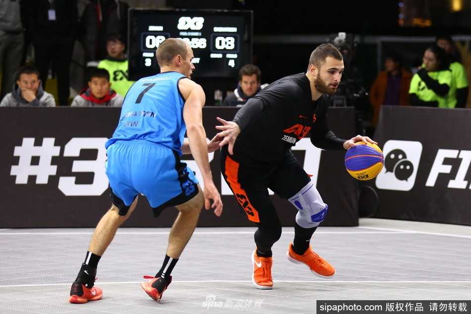 京城之夜诞生新王:塞尔维亚泽蒙队绝杀称霸三篮总决赛 决赛瞬间,身穿红色球衣的泽蒙队球员博格丹·德拉戈维奇在对方严防死守下高高跃起,准备出手绝杀球,他身后巨大的FIBA三对三赛事logo和记分牌将现场紧张气氛烘托到顶点。