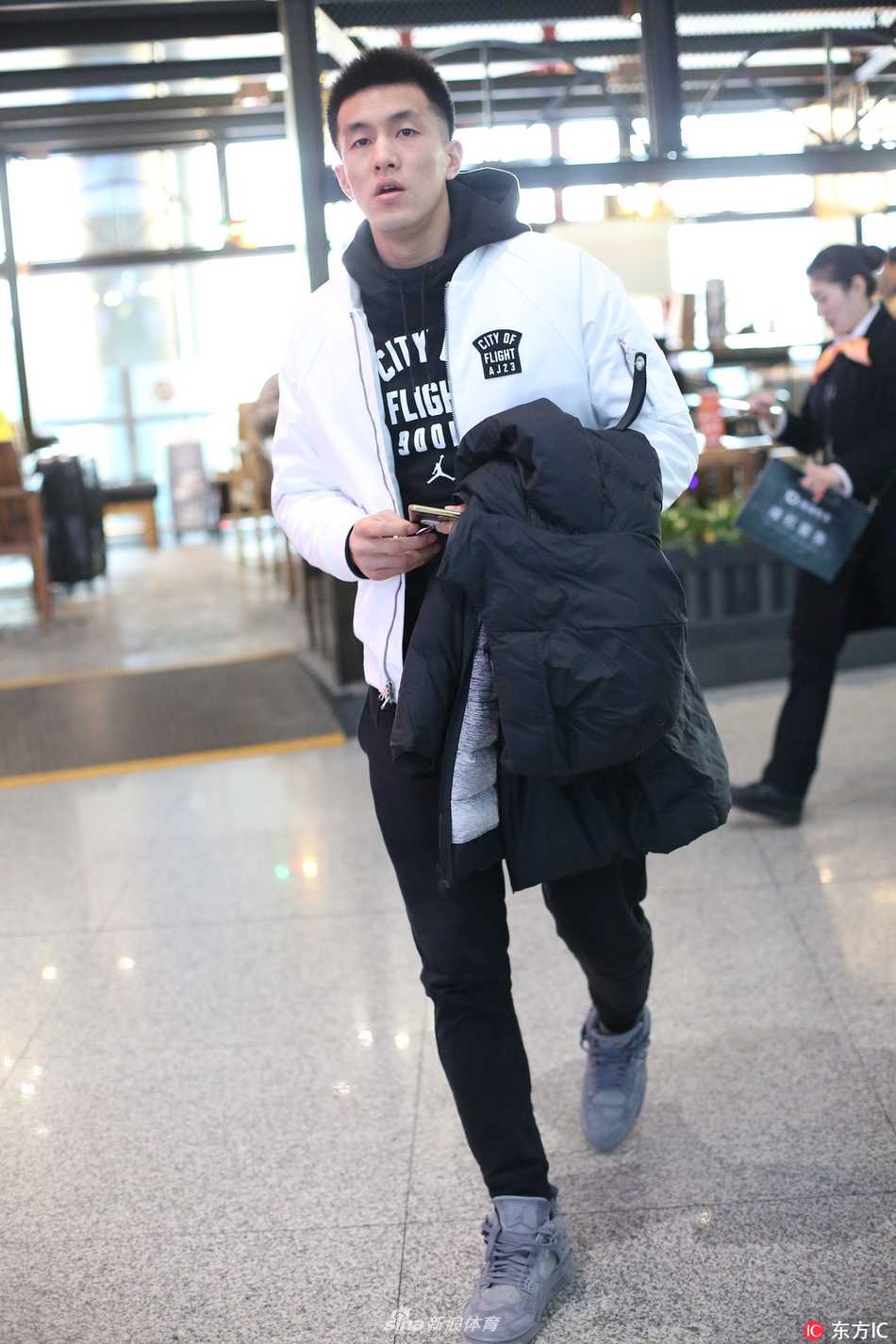 披上外套后，两人并肩而行，郭艾伦侧身倾听女友说话，脸上带着温和的笑意，画面温馨和谐，仿佛是冬日机场里一道最暖心的风景线。