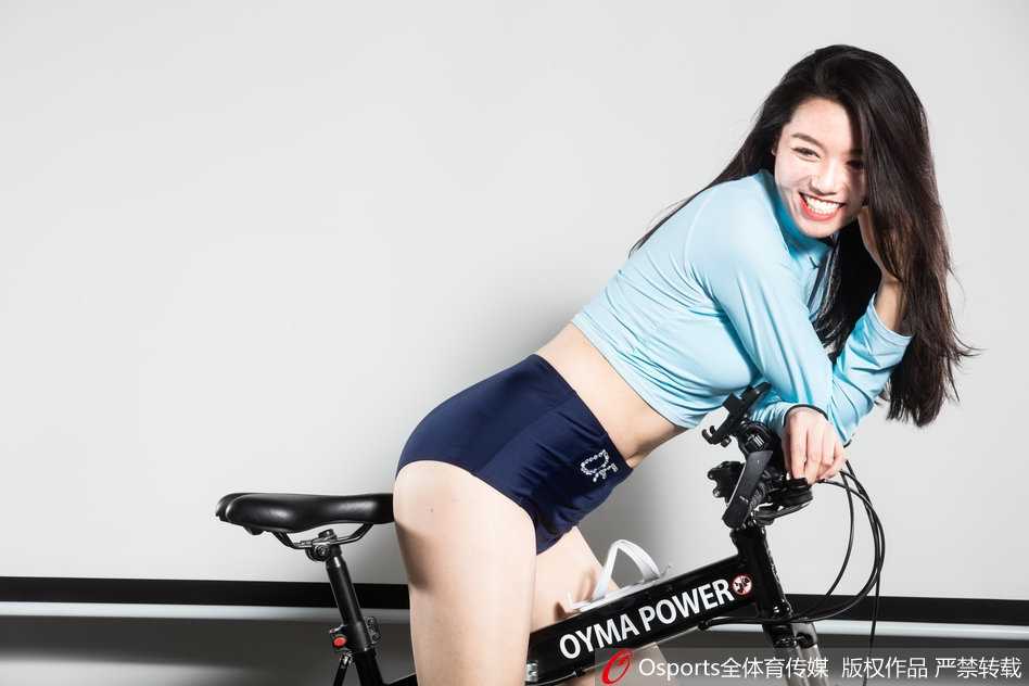 阳光洒落肩头，啦啦队员身穿亮眼红色热裤，在单车上侧身回眸，修长双腿线条流畅，仿佛下一秒就要蹬车飞驰。