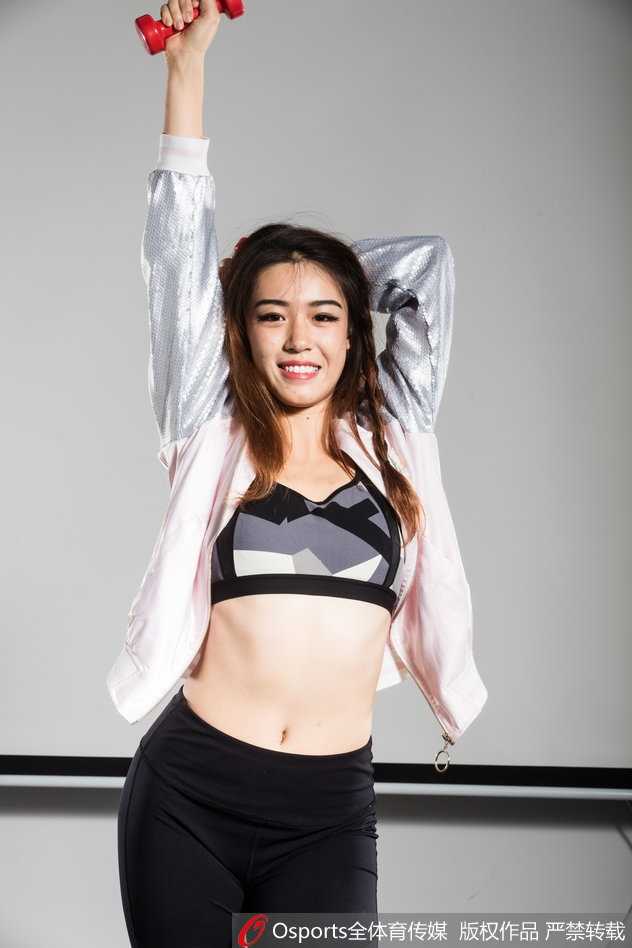 她单脚点地，轻松地坐在单车横梁上，热裤勾勒出动人曲线，背景的绿意更衬托出这份属于秋日的飒爽与明媚。