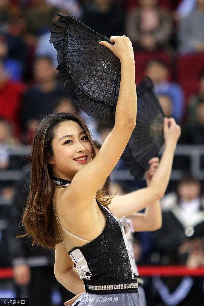 镜头聚焦于一位笑容灿烂的啦啦队员，她手中挥舞的花球划出优美的弧线，专注的神情仿佛在用舞蹈为场上拼搏的将士们传递力量。