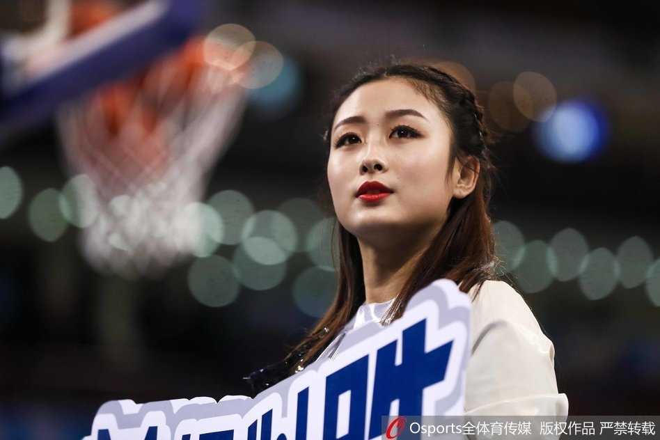 镜头拉近，一位身材高挑的篮球宝贝正侧身回眸，紧身热裤勾勒出健康的力量感，飞扬的发丝与自信的笑容，成为硬朗球场边最柔美的风景线