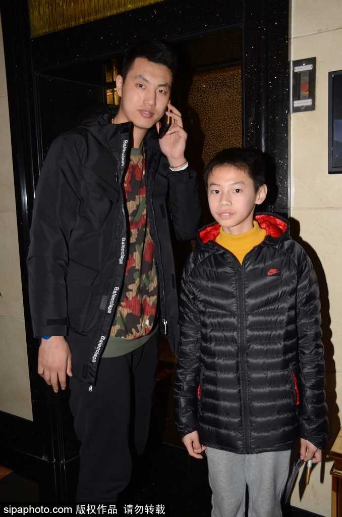 丘天咧嘴笑得开怀，俯身给小朋友签名，混血长相和灿烂笑容让他成为人群中焦点