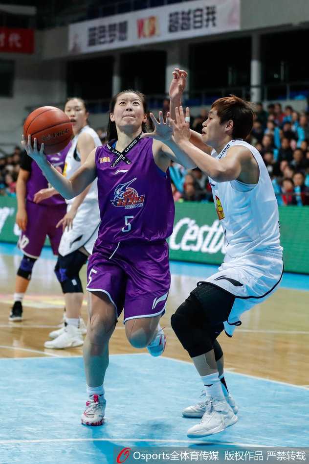 上海队球员在严密防守下奋力跃起投篮，尽管比分落后，但她们拼搏的斗志从未熄灭。
