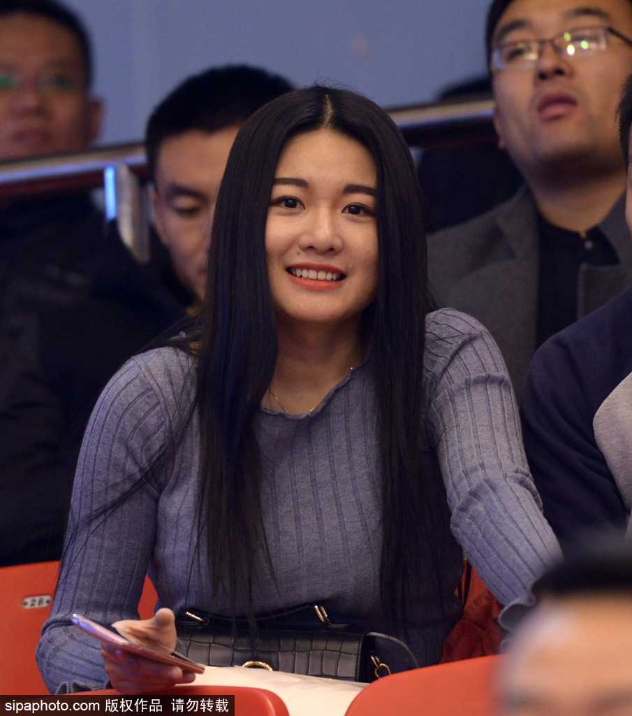 丁彦雨航在加时赛中持球突破，面对北京队的双人包夹毫无惧色，他的眼神坚毅如铁，全场球迷起立注视，看台前排一位美女球迷紧握双手放在胸前，神情紧张又充满期待。