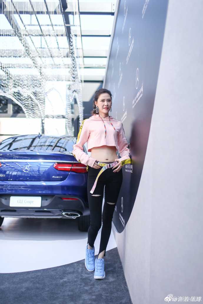 许诺身穿粉色露脐装，盈盈笑意中透着飒爽，高挑身材与豪车相映成辉，一双笔直美腿格外吸睛。