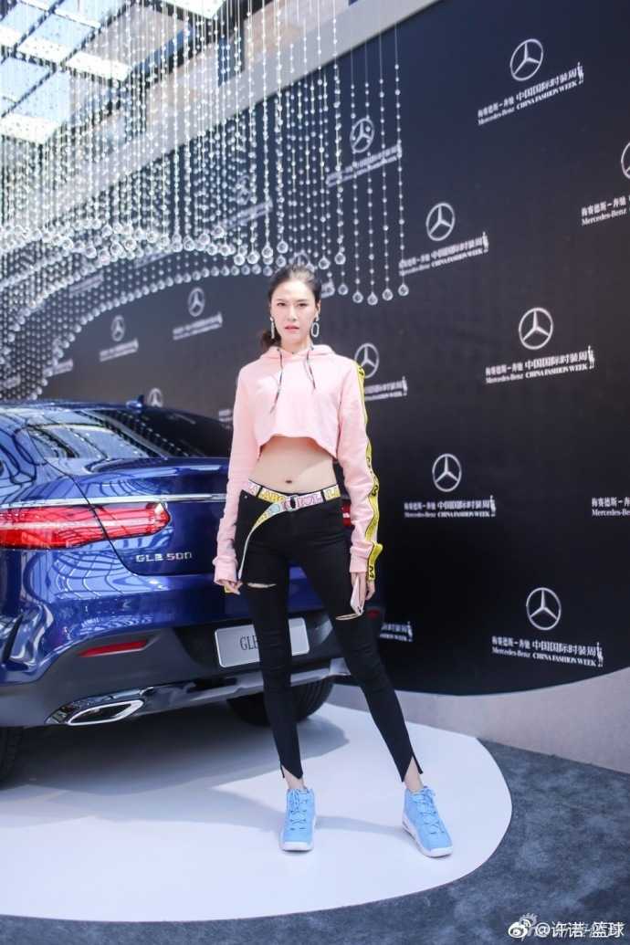 许诺轻倚豪车旁，粉色短衫在阳光下泛起柔光，超高腰线设计更显身姿挺拔，俨然一道靓丽的都市风景线。