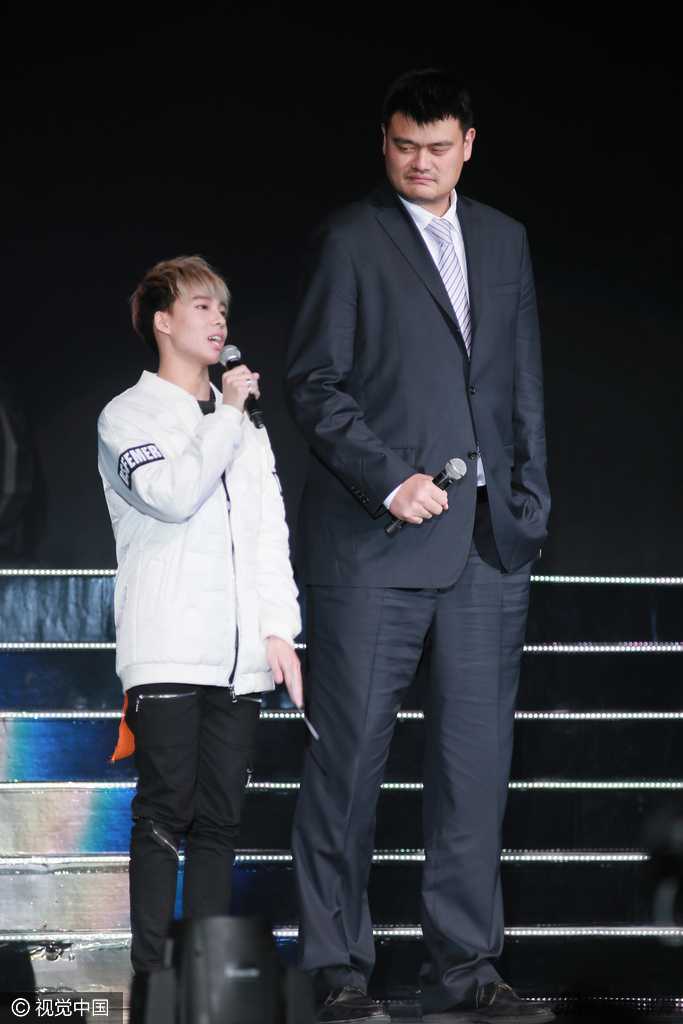 特写镜头下，姚明神情专注地看向舞台远方，周围是模糊的观众身影，此刻他不是球星，只是一位沉浸在音乐氛围中的普通观众。