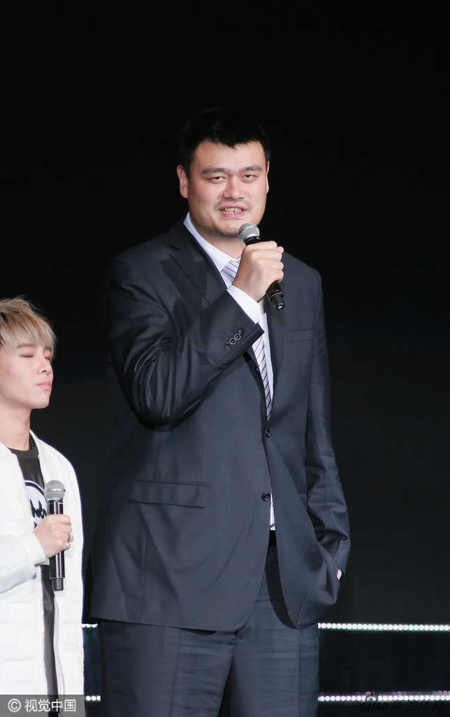 面对热情的香港观众和台上的歌手，姚明露出标志性的憨厚笑容，挥手致意，如同一个温和的巨人在分享新年的喜悦与祝福。