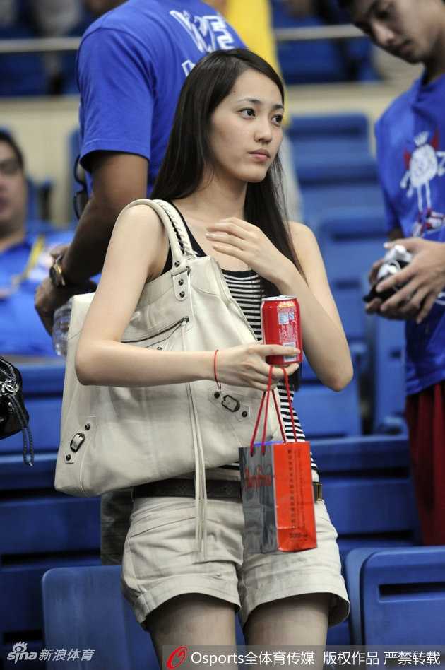 王棠云身穿深色外套站在球场通道内，双手插兜回眸面对镜头，身后是空荡的坐席与明亮的灯光