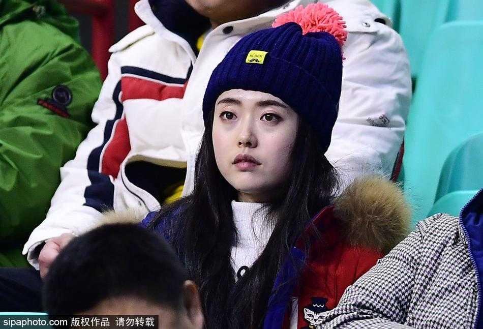 球场灯光的余晖洒在这位短发女孩的侧脸上，勾勒出一道迷人的金色轮廓。她微微侧身，眼神专注而深邃，仿佛能洞察球场上瞬息万变的战局，清冷的气质与身后热烈的氛围形成极具张力的对比。