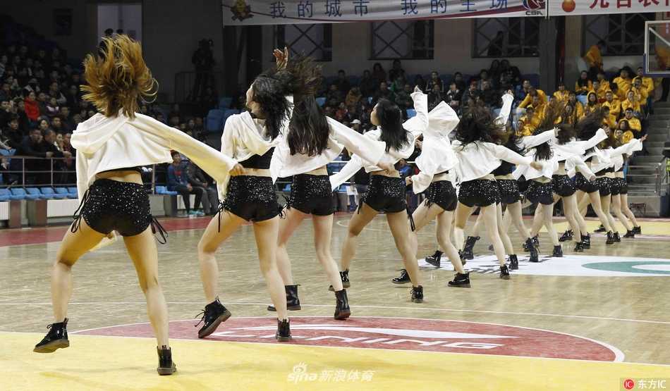 可爱的吉祥物“东北虎”单膝跪地，向面前的啦啦宝贝做出“求婚”的搞笑动作，宝贝则掩面而笑，这一幽默互动让紧张的比赛氛围变得轻松愉悦。