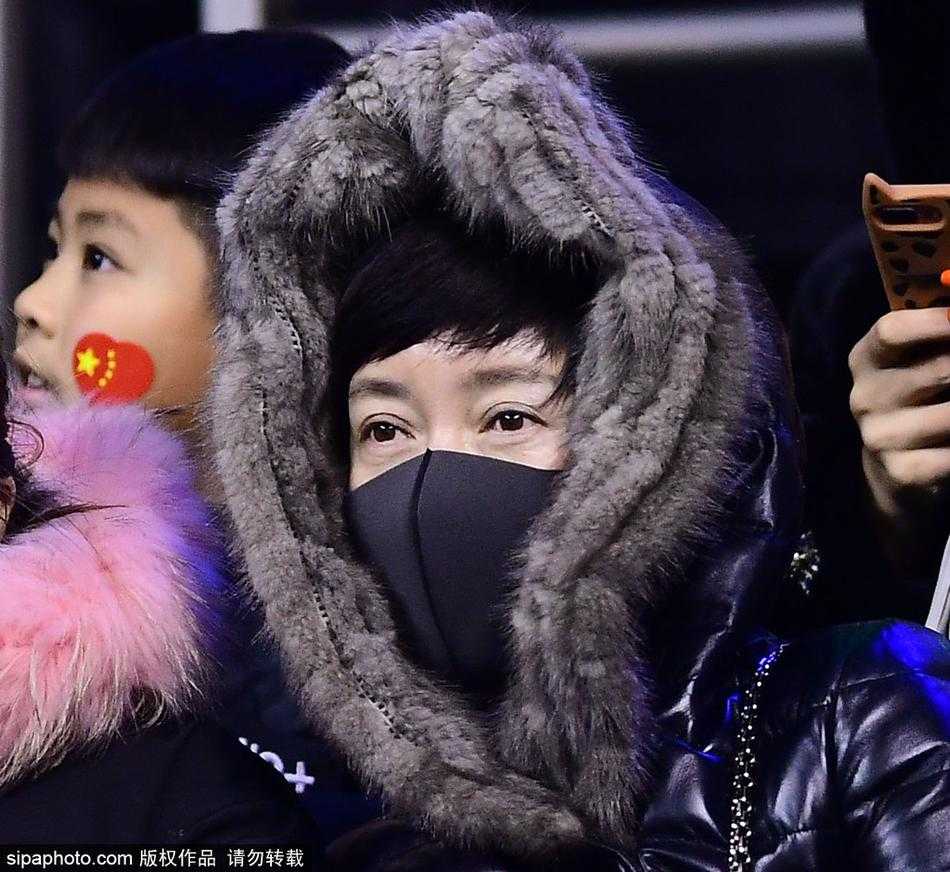 一位中年男球迷戴着厚厚的皮手套，双手举着为自己制作的加油牌，口中似乎正高喊着口号。他呼出的白色哈气在脸前飘散，与看台上其他同样包裹严实的观众融为一体，构成了一幅生动且充满温度的冬日看台画卷。