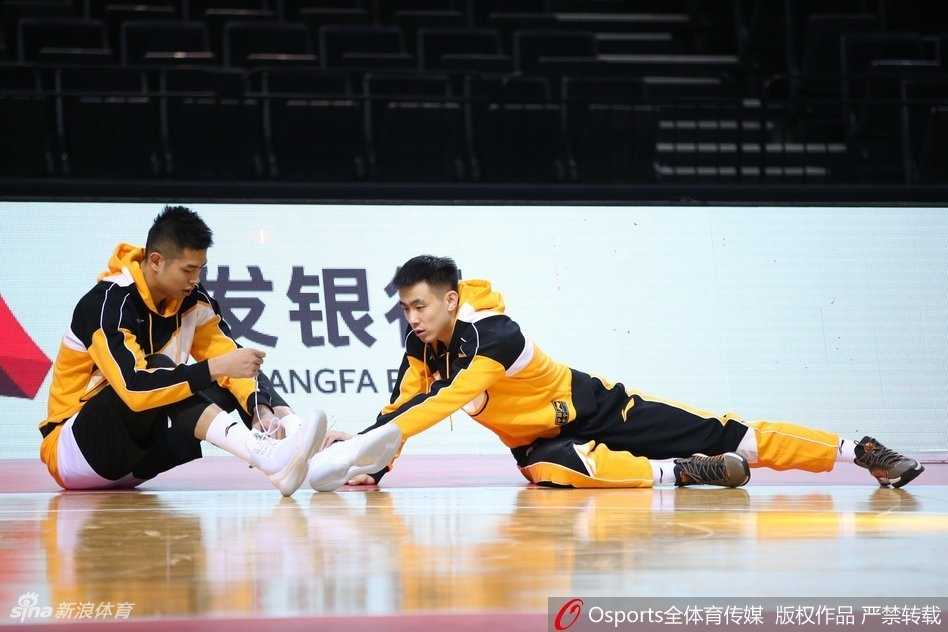 队友在练习运球，郭艾伦却像个顽皮的孩子一样突然从背后伸出双手试图掏球，恶作剧得逞后脸上立刻绽放出灿烂又得意的笑容。