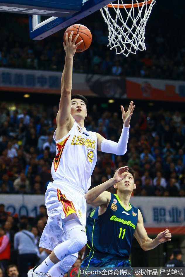 广东队任骏飞犹如一辆坦克般强行突破上篮，在身体对抗中动作变形，但仍奋力将球抛出，展现了极强的攻击欲望。
